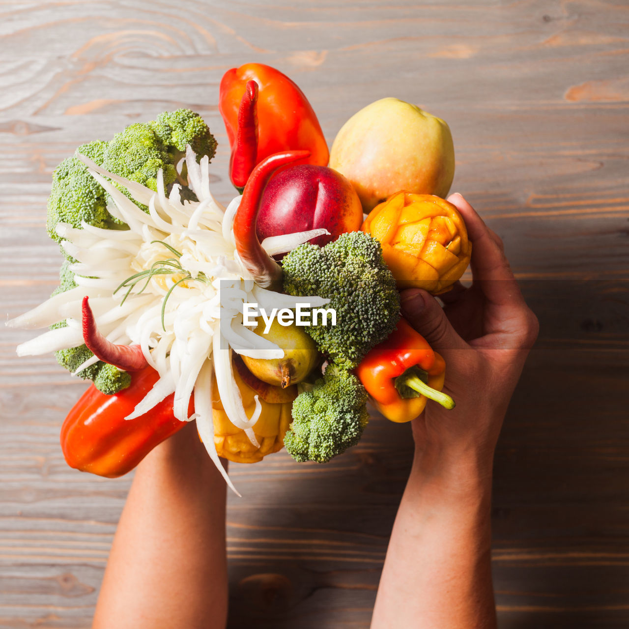 Cropped hands of person holding vegetables over table