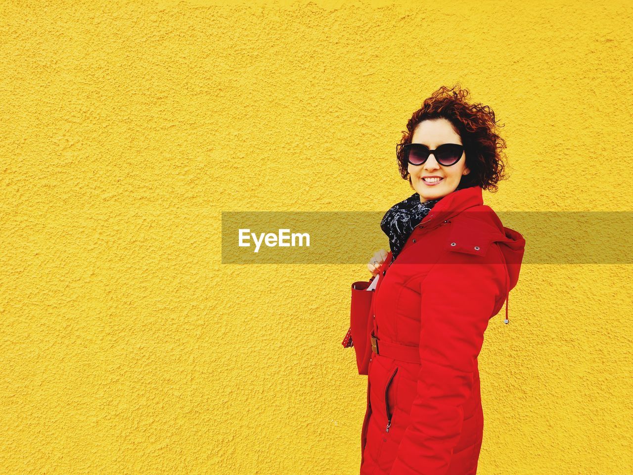 Portrait of young woman standing against yellow wall