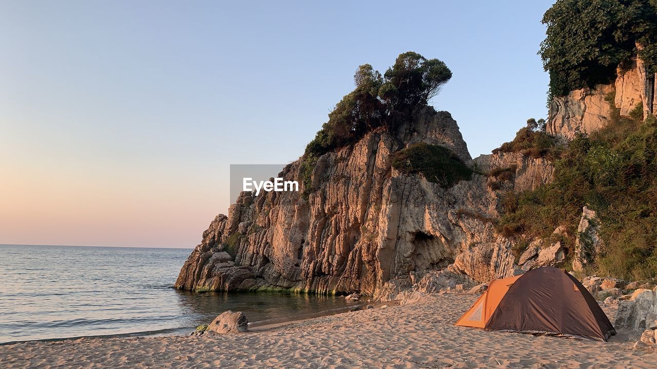 Rock formations on shore by sea against clear sky