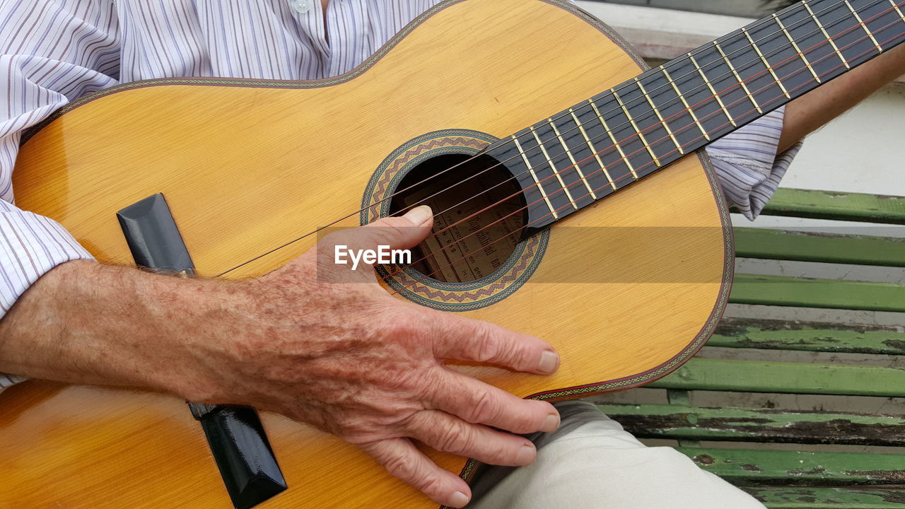 Midsection of man playing guitar