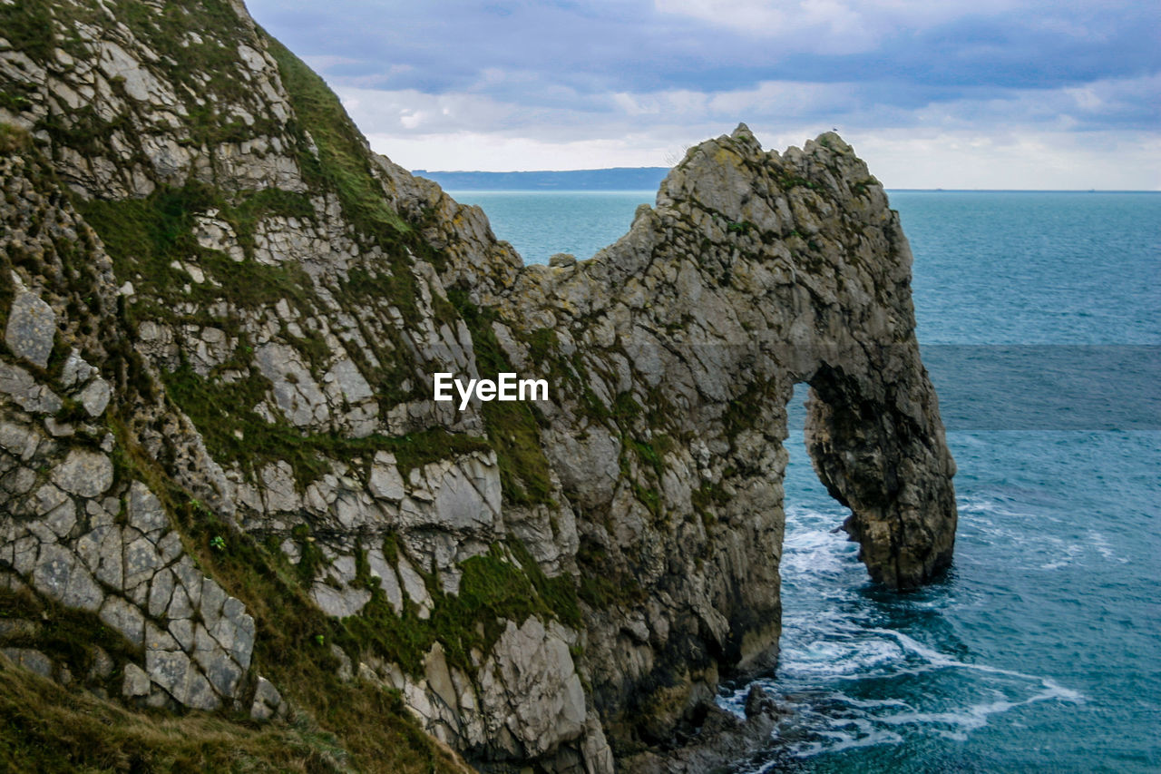 Scenic view of cliff by sea against sky