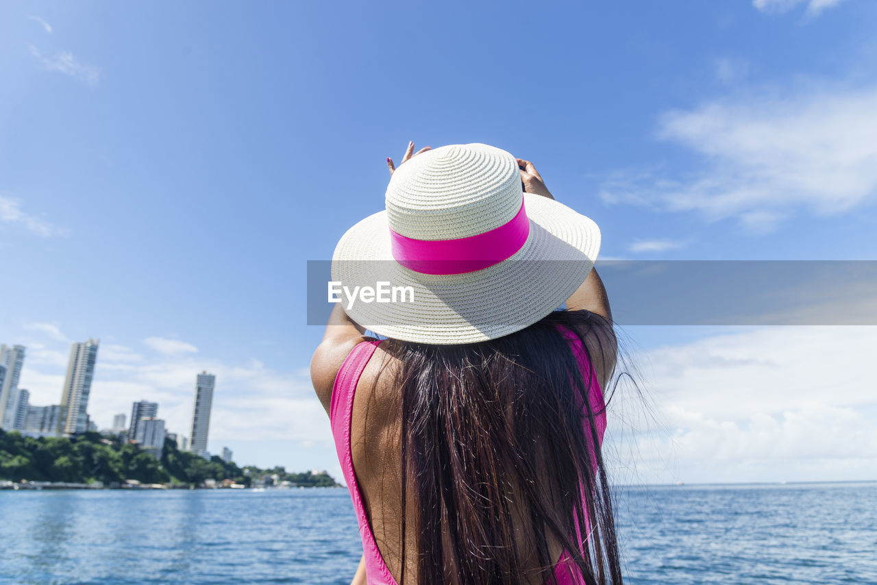 A woman on top of a boat against the sea in the background. 