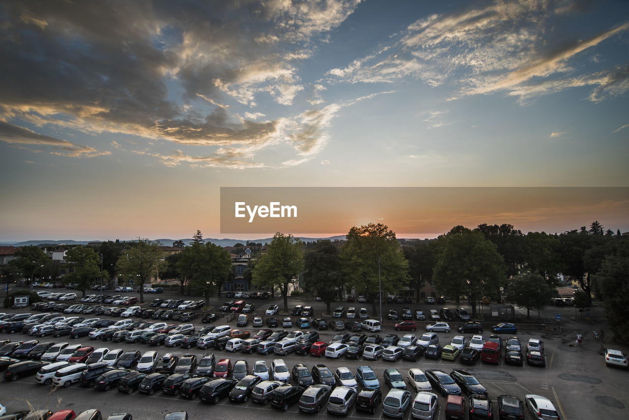 Cars parked in parking lot against sky during sunset