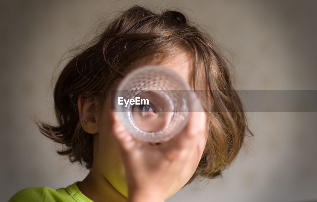 Portrait of boy looking through drinking glass