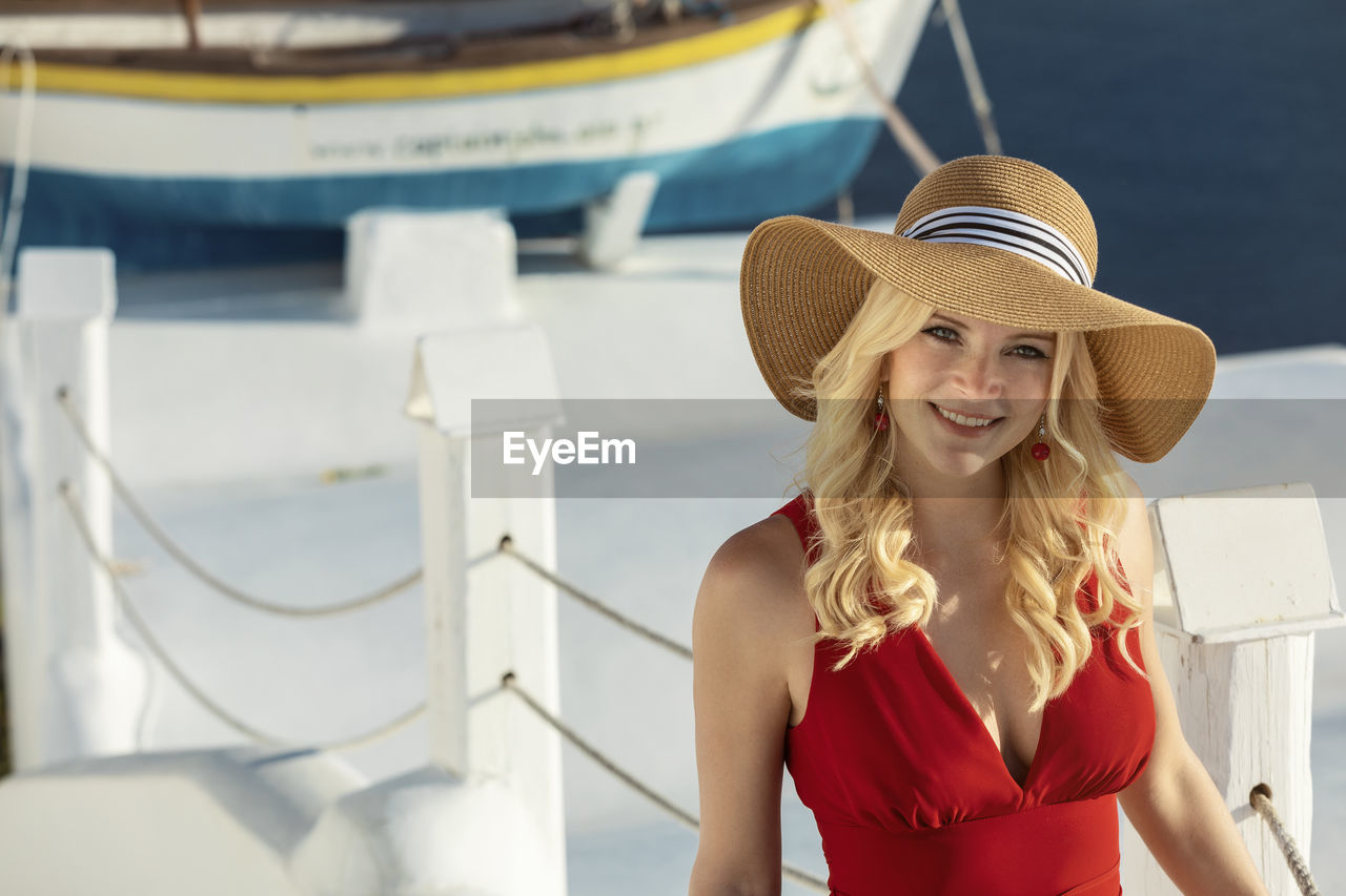 Portrait of smiling woman wearing hat standing by railing