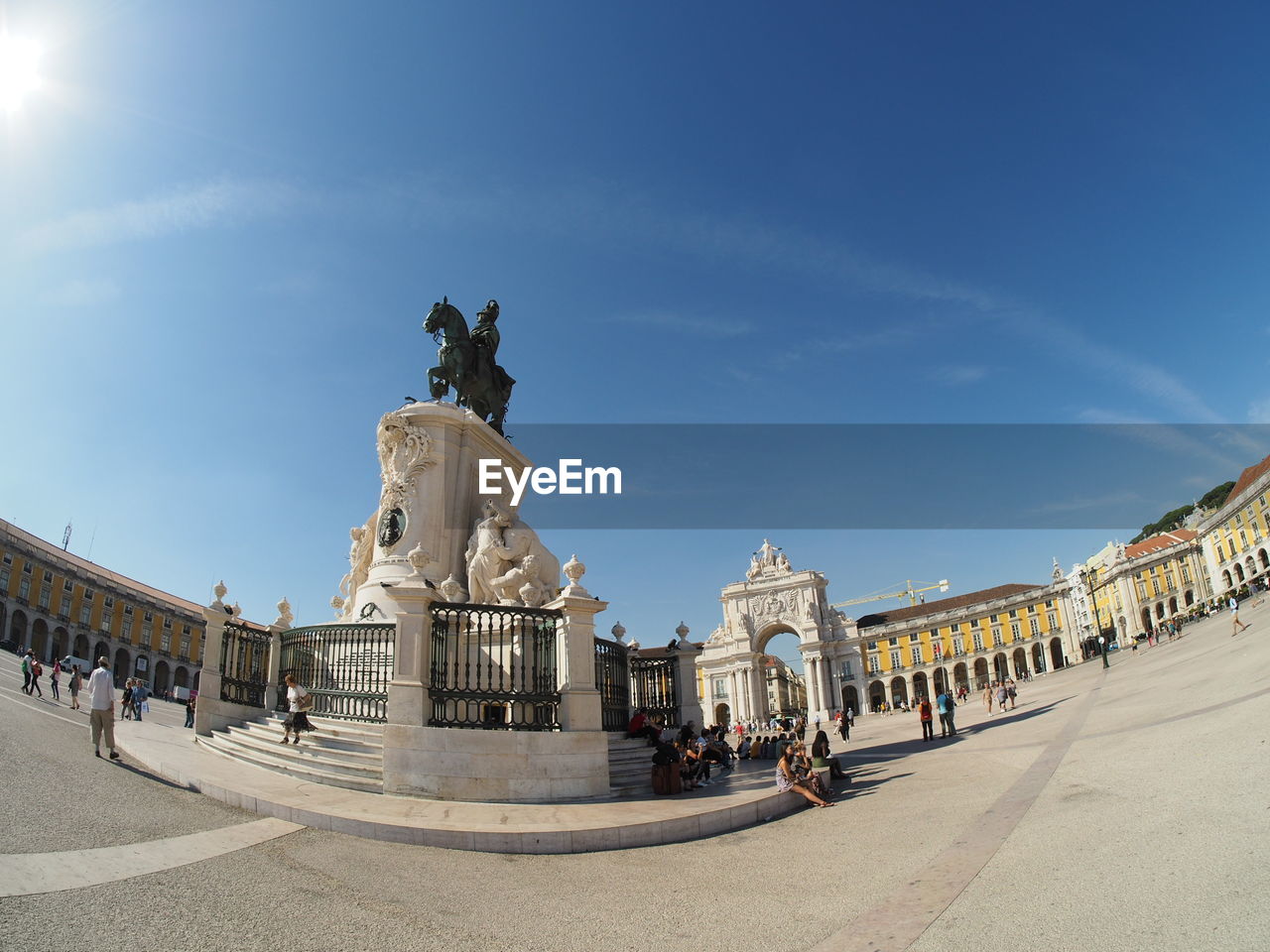 Fish-eye view of statue at town square against blue sky