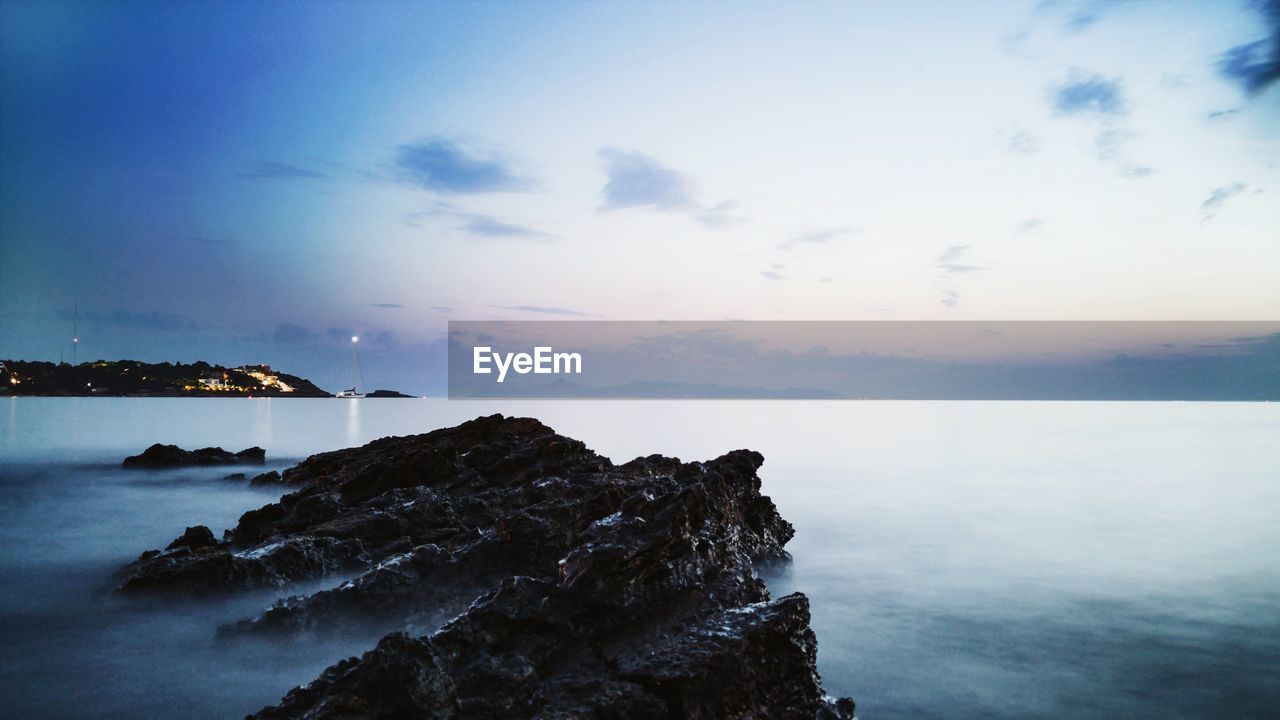 Rock formations in sea at sunset