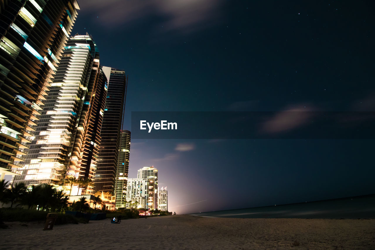 Buildings by beach in city at night