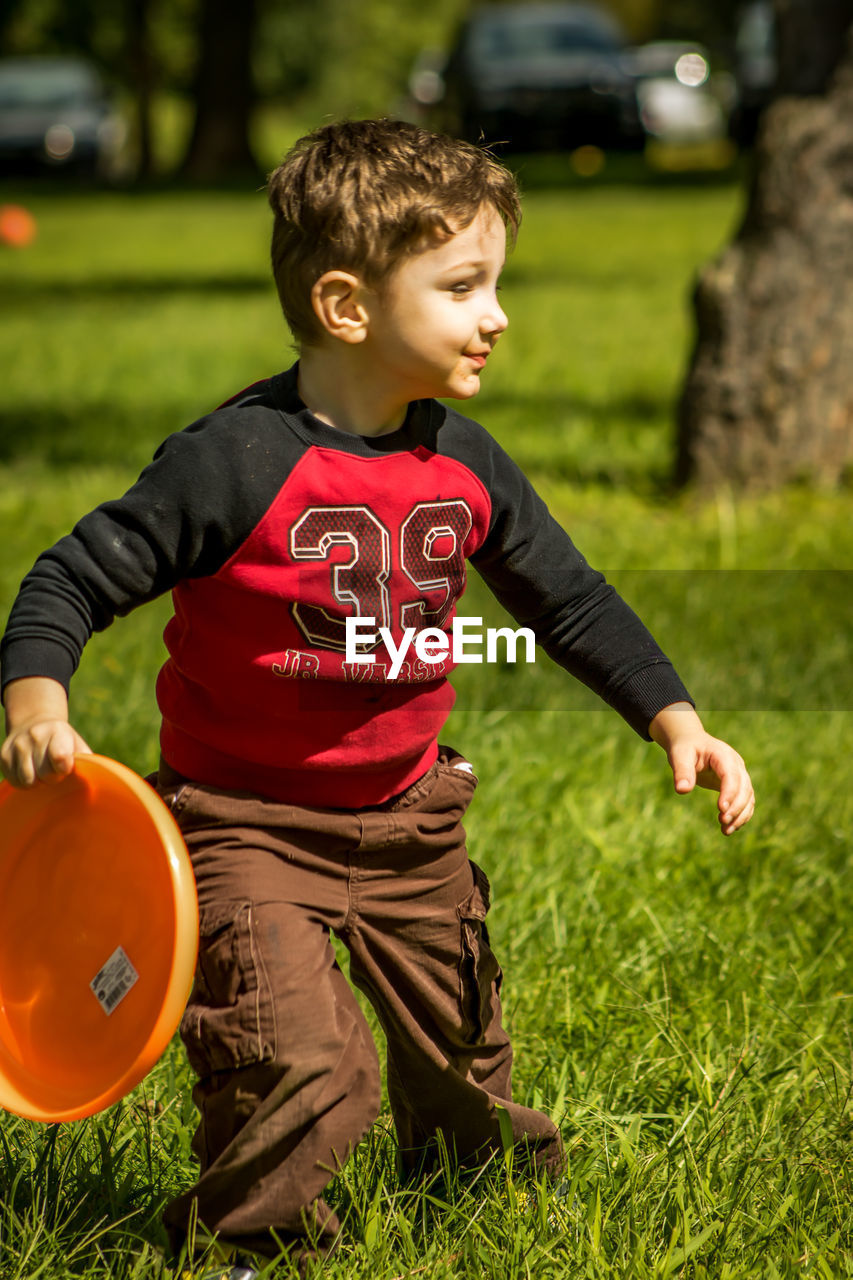 Boy playing with plastic disc on grassy field