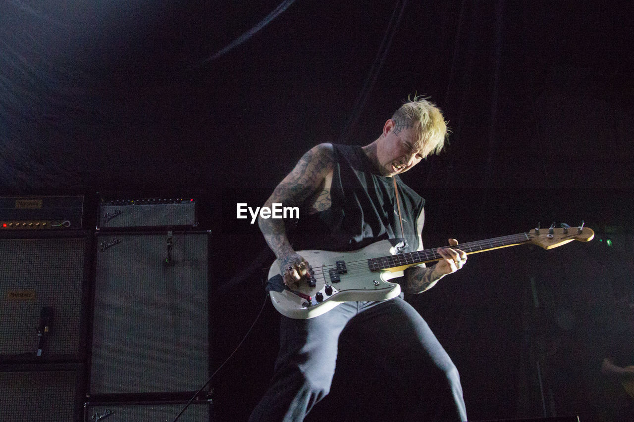 FULL LENGTH OF MAN PLAYING GUITAR ON STAGE