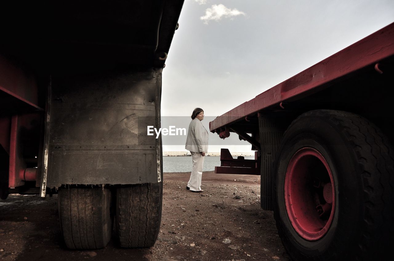 Full length of woman standing by trucks against sky