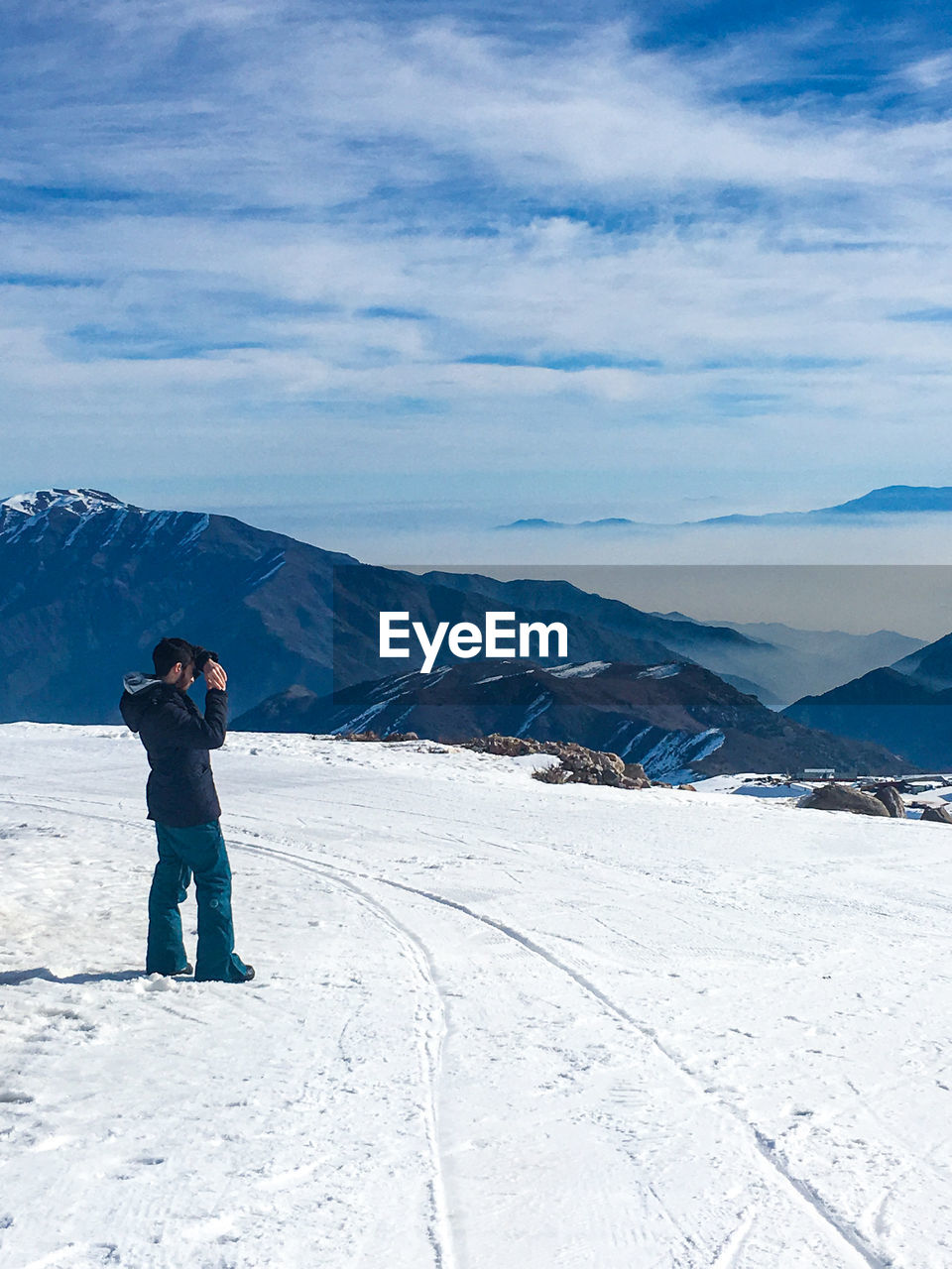 Side view of man standing on snow covered land against sky