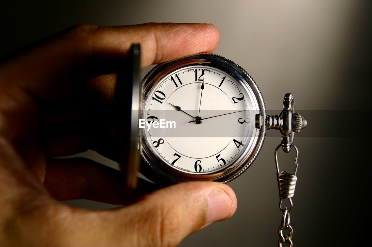 Cropped image of hand holding pocket watch