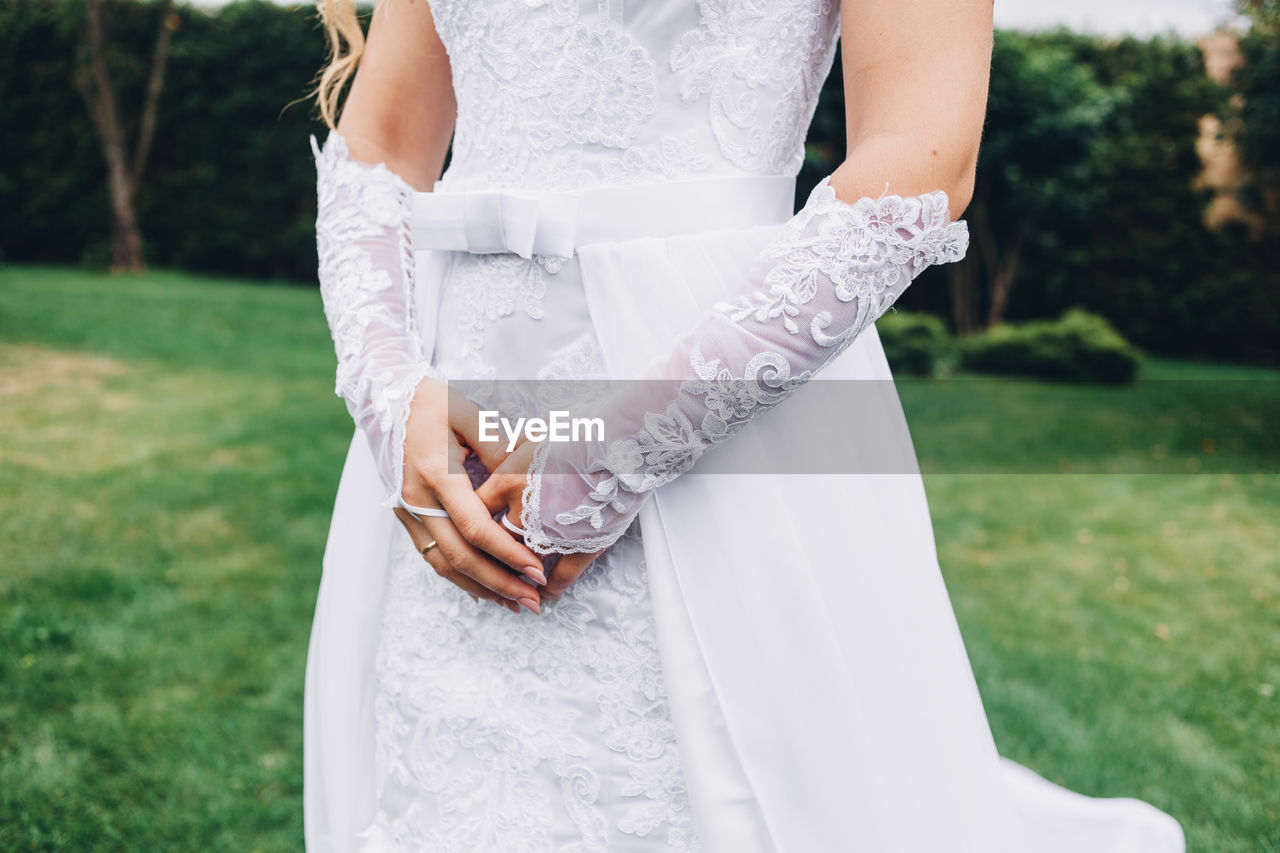 Midsection of bride standing at park