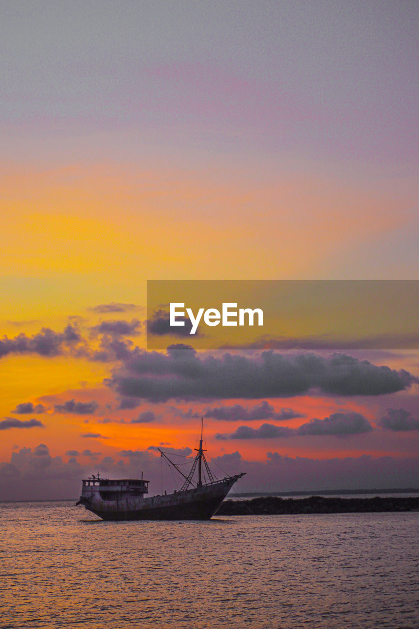 Sailboat in sea against sky during sunset