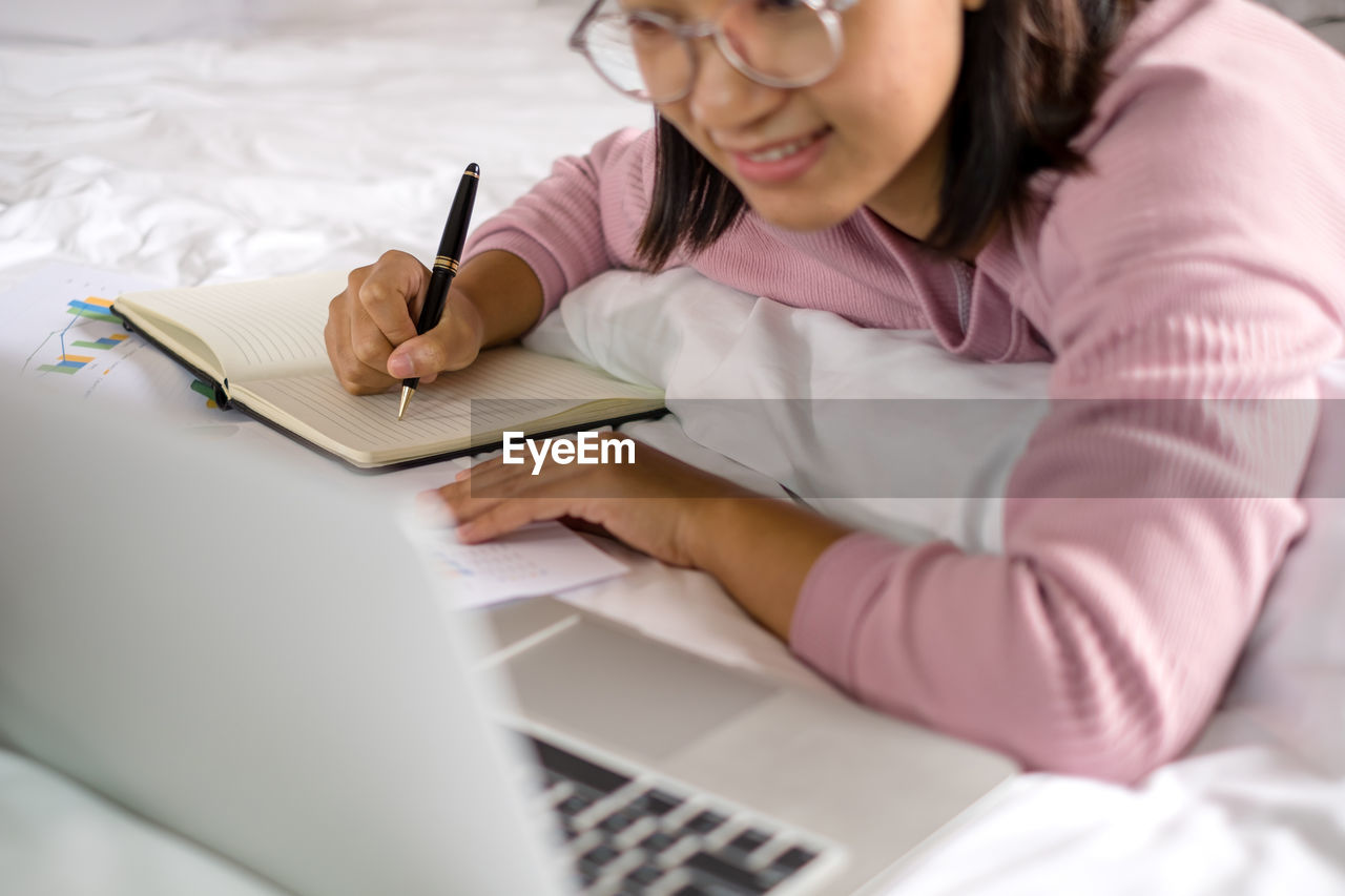 Midsection of businesswoman writing in notebook