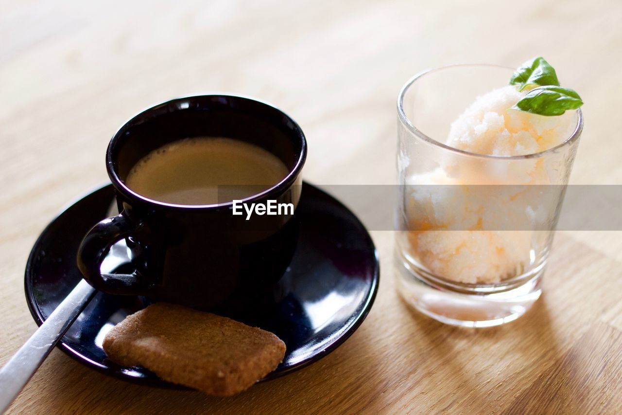 Coffee cup with cookie and sorbet in glass garnished with mint leaves