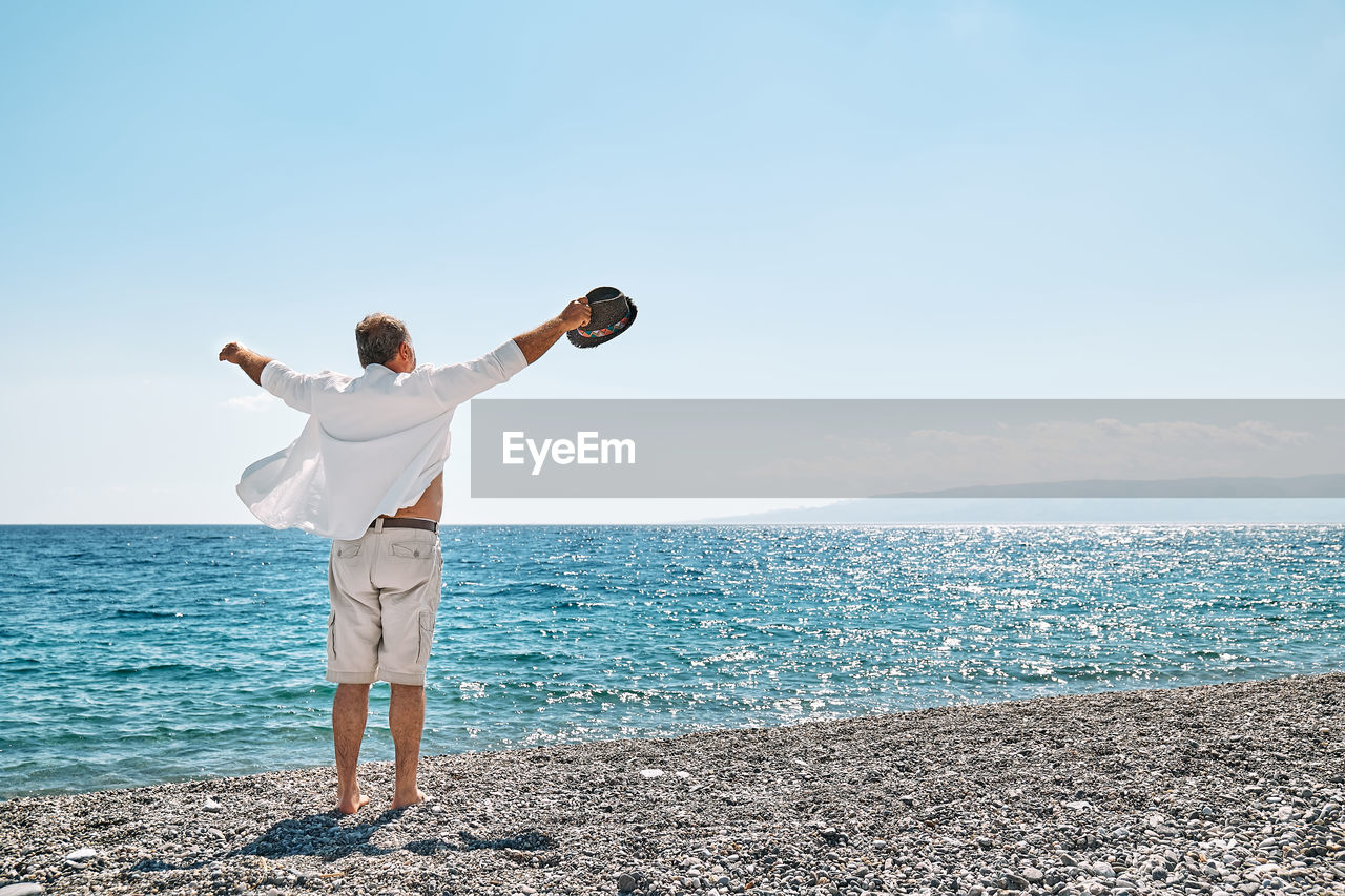 Happy middle-aged man enjoying freedom with open hands on sea. wellness, success,freedom and travel