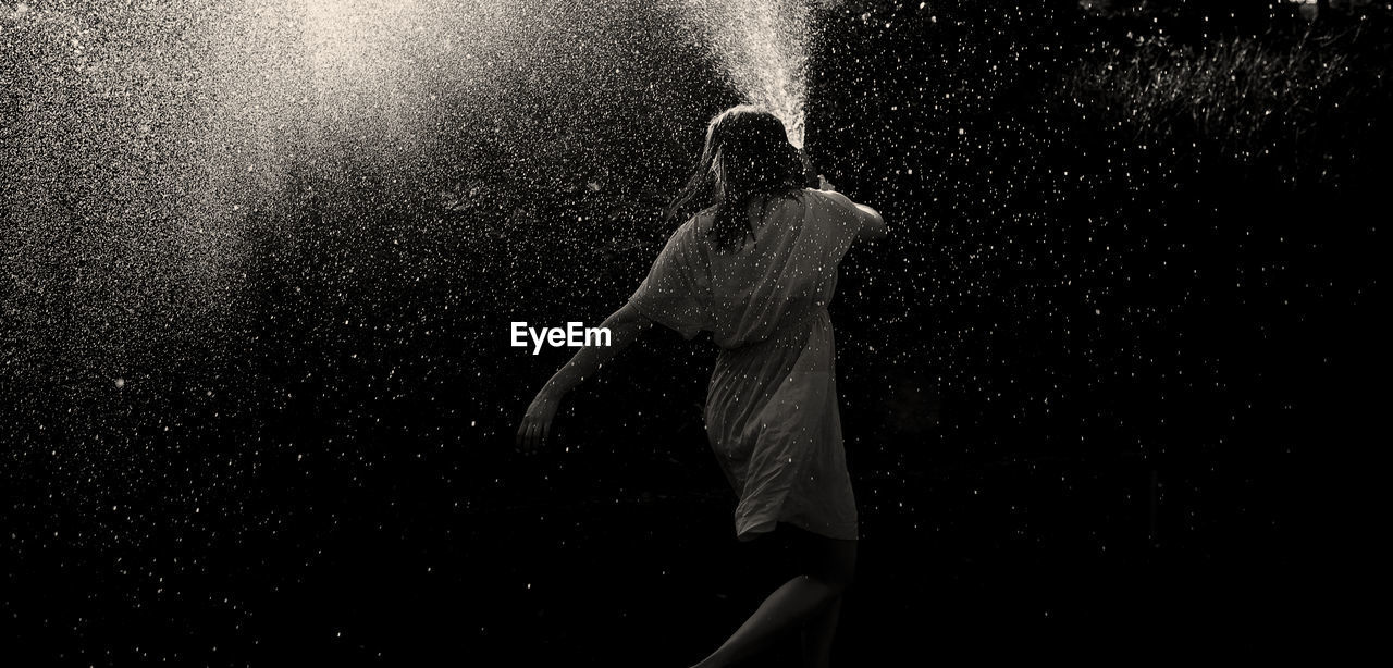 Woman spraying water through gardening hose