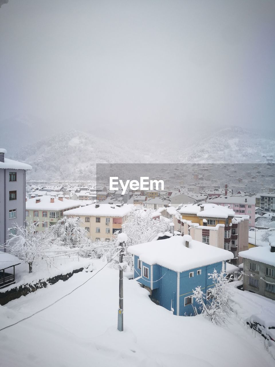 High angle view of snow covered houses and buildings against sky