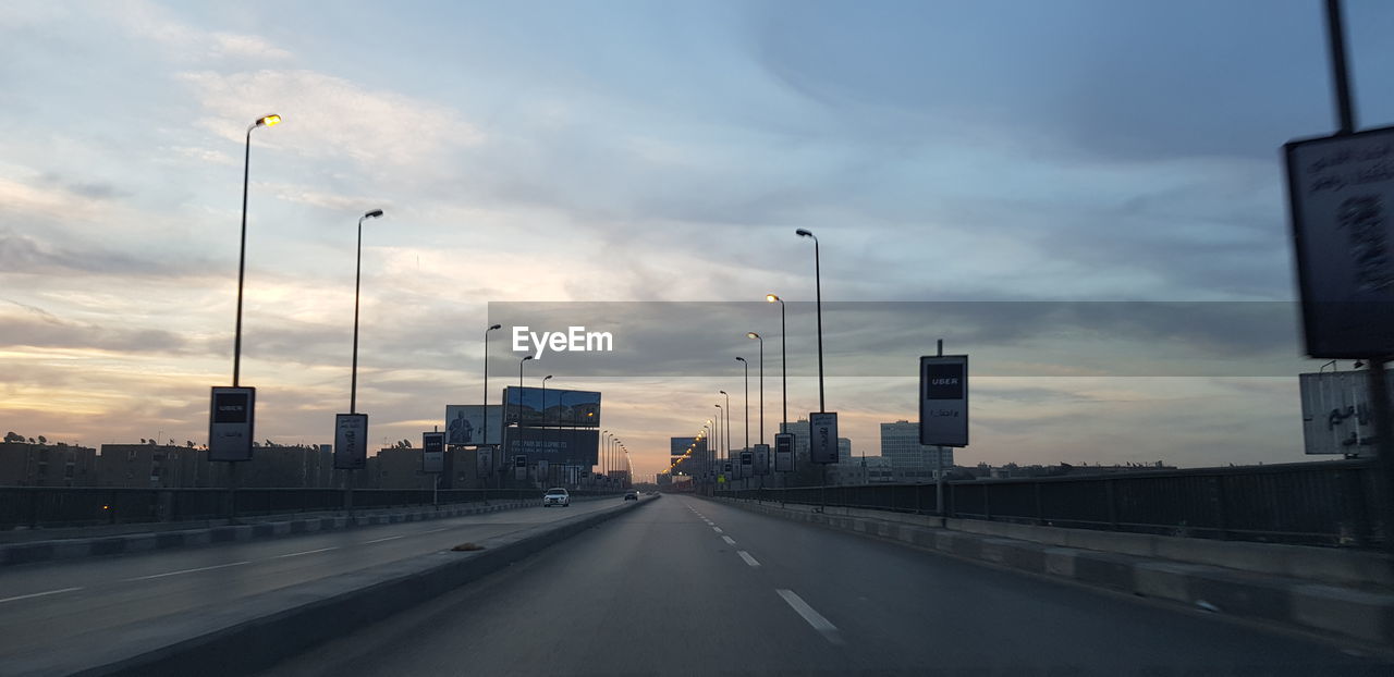 Road by highway against sky in city