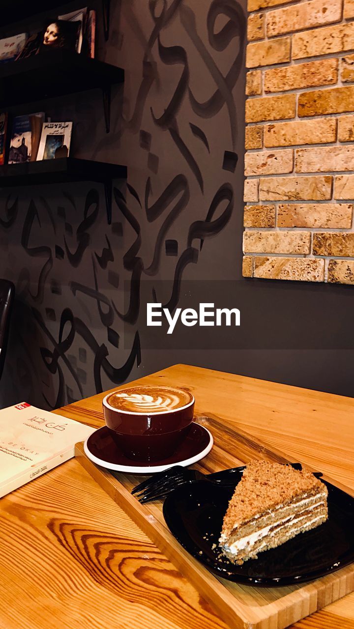 HIGH ANGLE VIEW OF COFFEE CUP ON TABLE AGAINST WALL