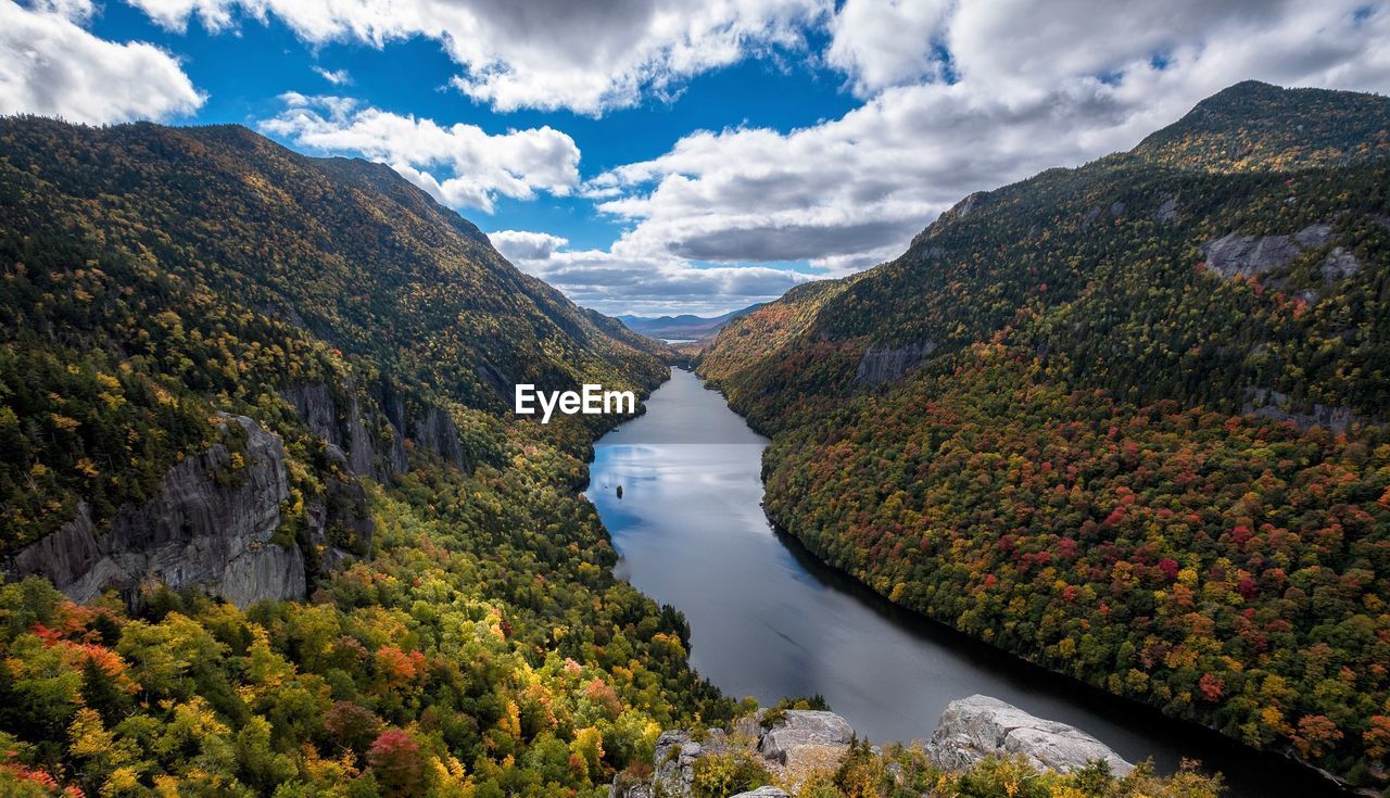 Scenic view of river amidst tree mountains against sky during autumn