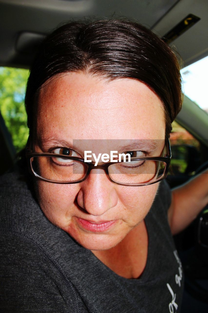 Portrait of serious woman wearing eyeglasses traveling in car