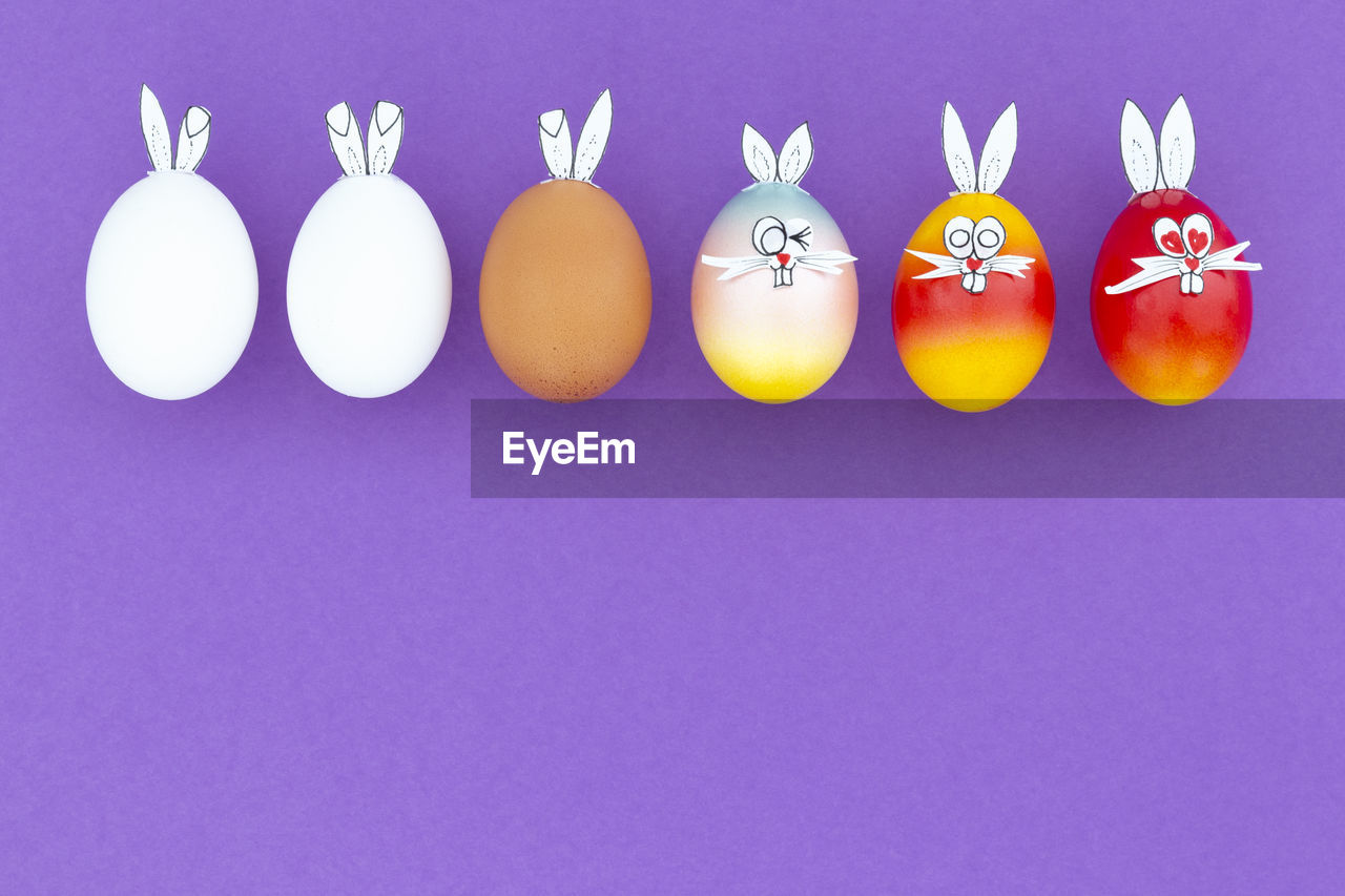 White, brown and colorful easter eggs with funny bunny ears and cartoon faces on white background