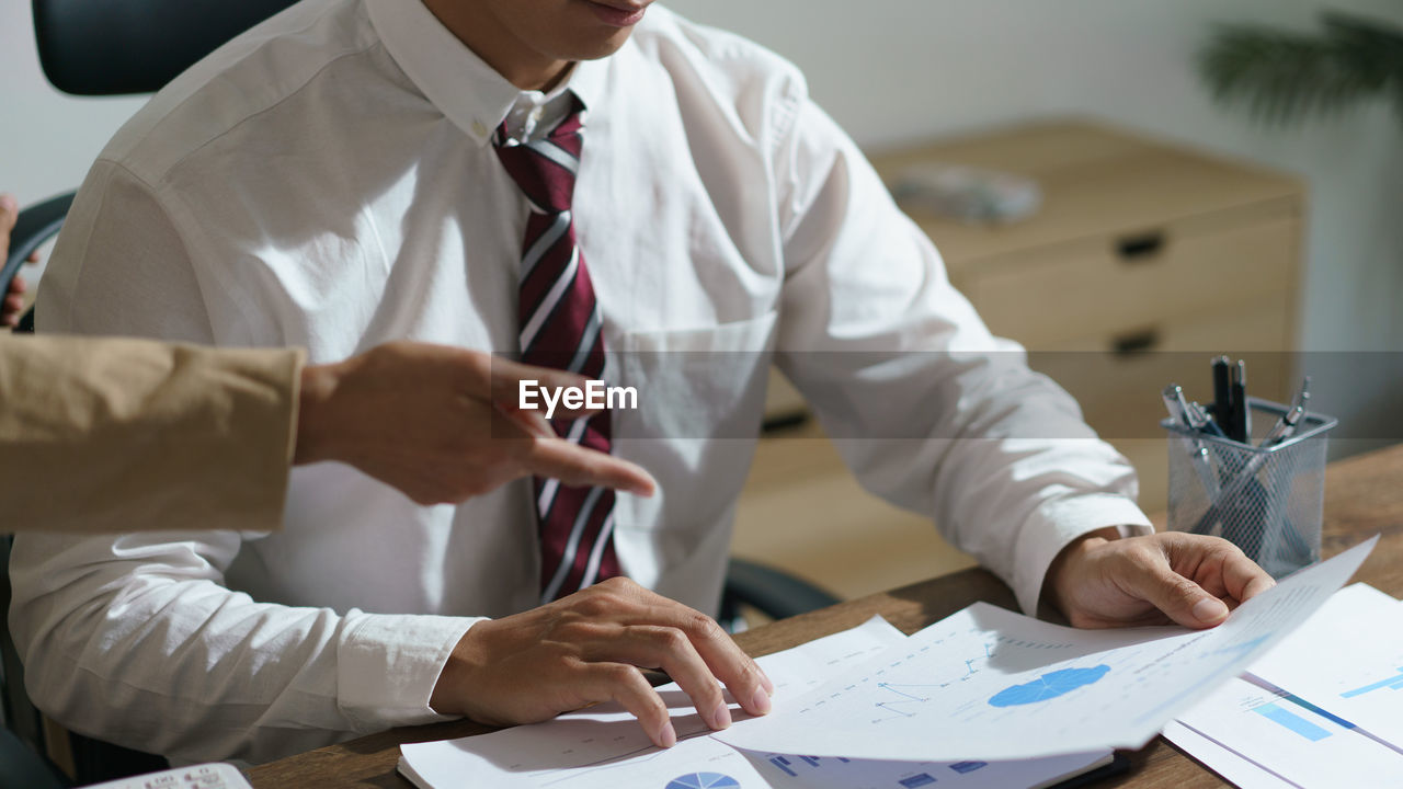 midsection of business colleagues working at desk in office
