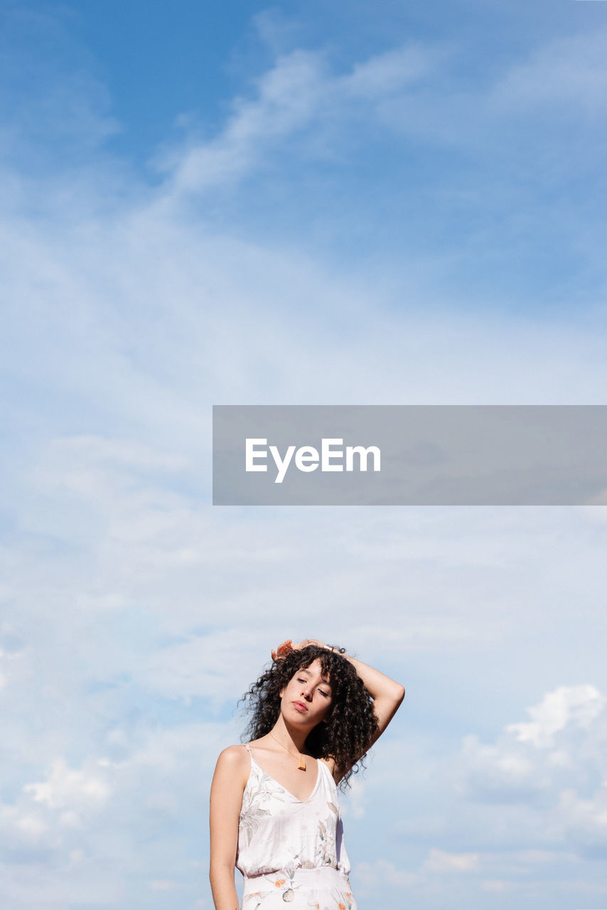 PORTRAIT OF A YOUNG WOMAN AGAINST SKY