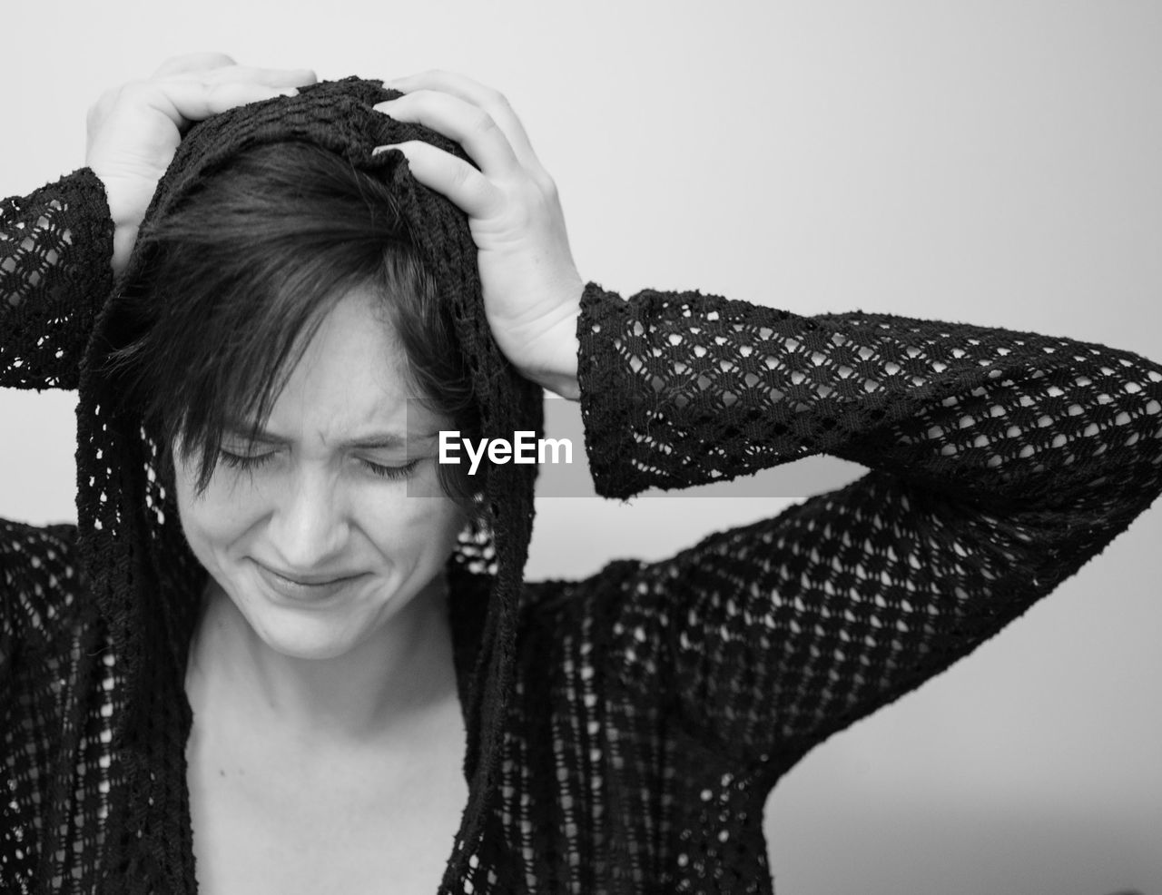 Close-up of young woman holding head during headache against wall