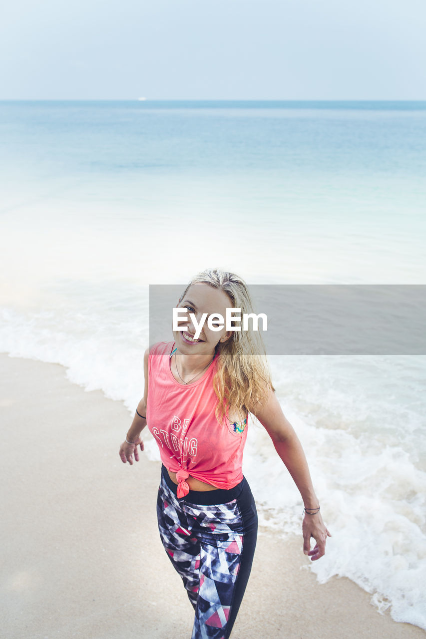 Portrait of smiling mid adult woman standing on beach