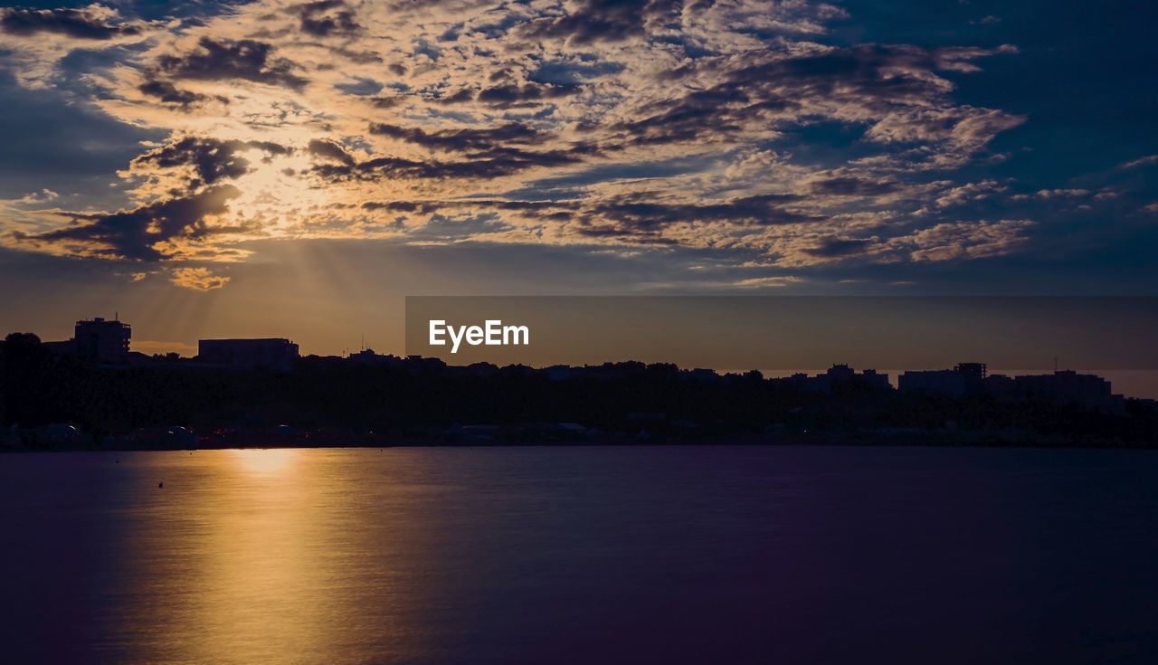 SCENIC VIEW OF SEA BY BUILDINGS AGAINST SKY AT SUNSET