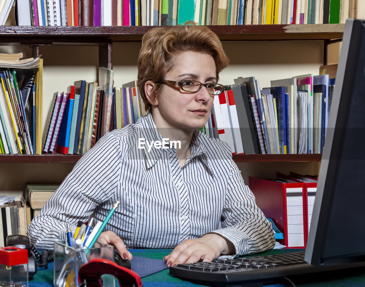 Portait of a busy woman working at her desk at the home. 