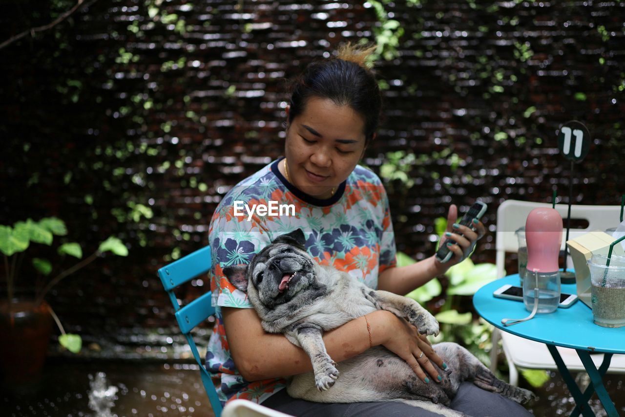 Smiling woman sitting with dog outdoors