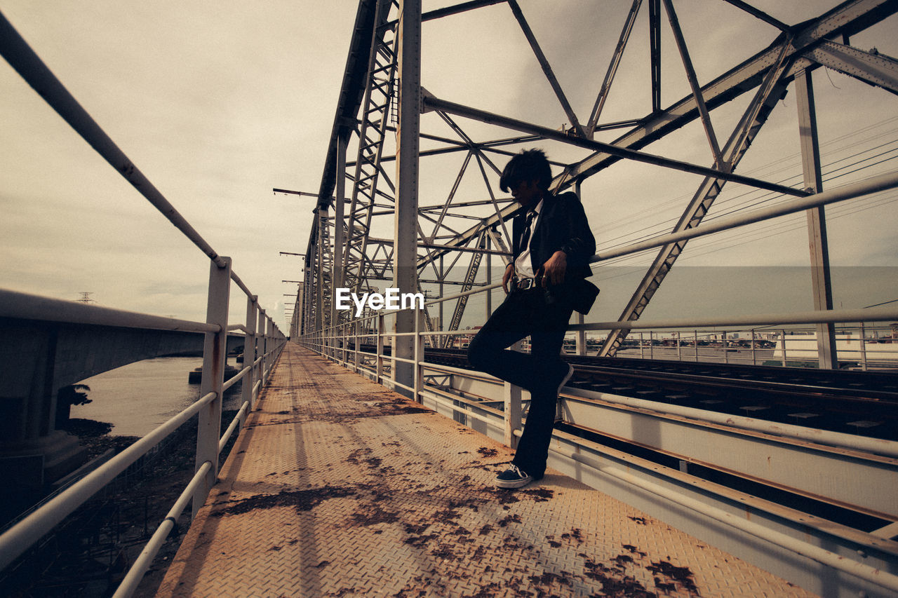 architecture, one person, sky, track, transportation, railroad track, full length, built structure, rail transportation, adult, bridge, nature, transport, silhouette, men, lifestyles, line, outdoors, electricity, urban area, travel, person, city, day, motion, standing