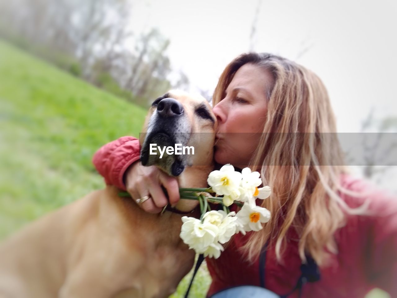 MIDSECTION OF WOMAN WITH DOG AT FLOWER