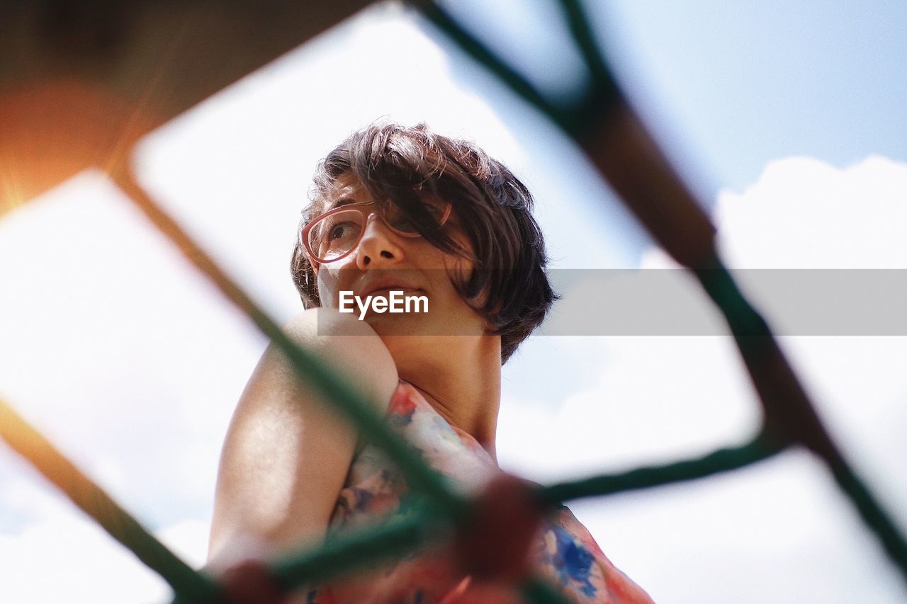 Low angle view of thoughtful woman standing against sky