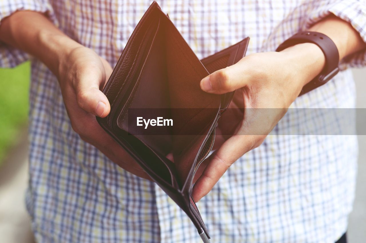 Midsection of man holding empty wallet