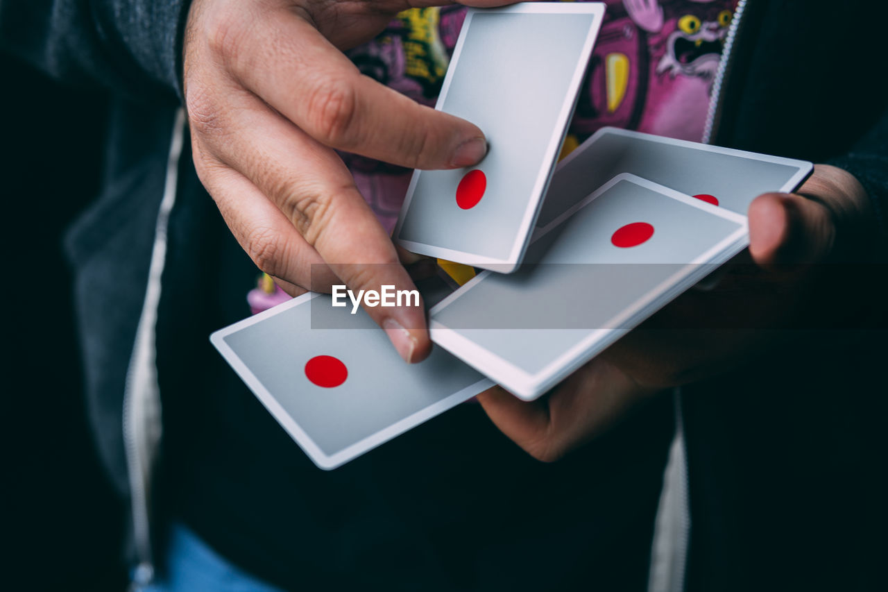 Midsection of person holding playing cards