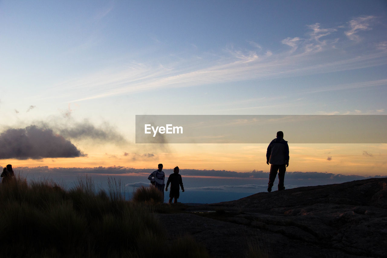 Silhouette hikers on mountain against sky during sunset