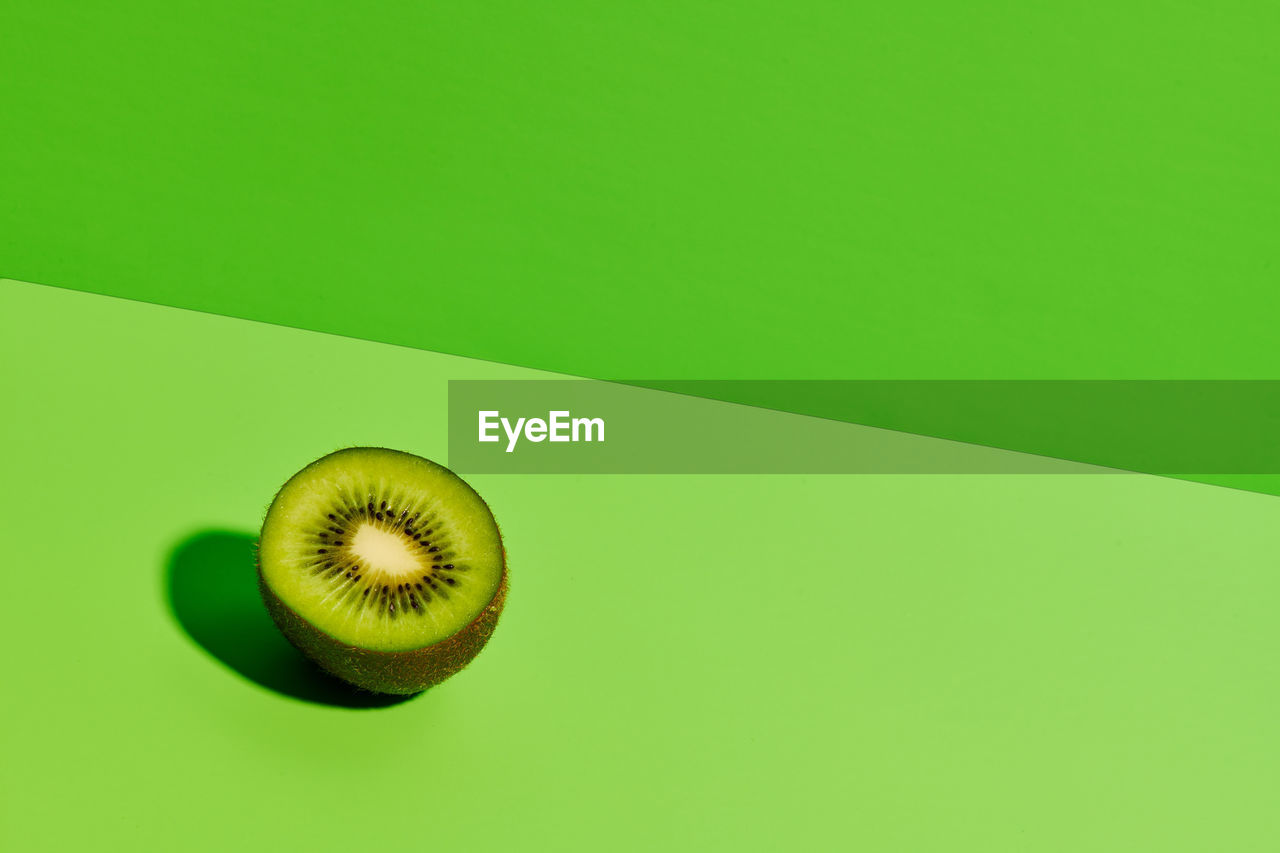 Half of delicious ripe kiwi fruit placed on green background in modern studio