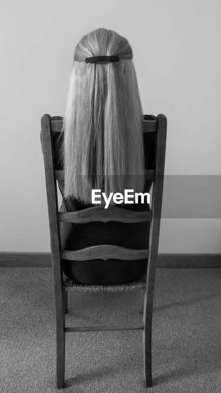 Rear view of woman with long hair sitting on chair
