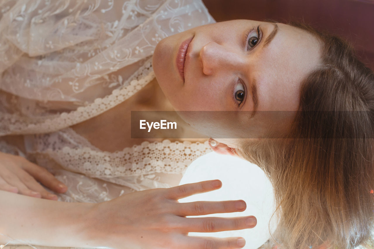 Close up woman laying head on glowing ball lamp portrait picture