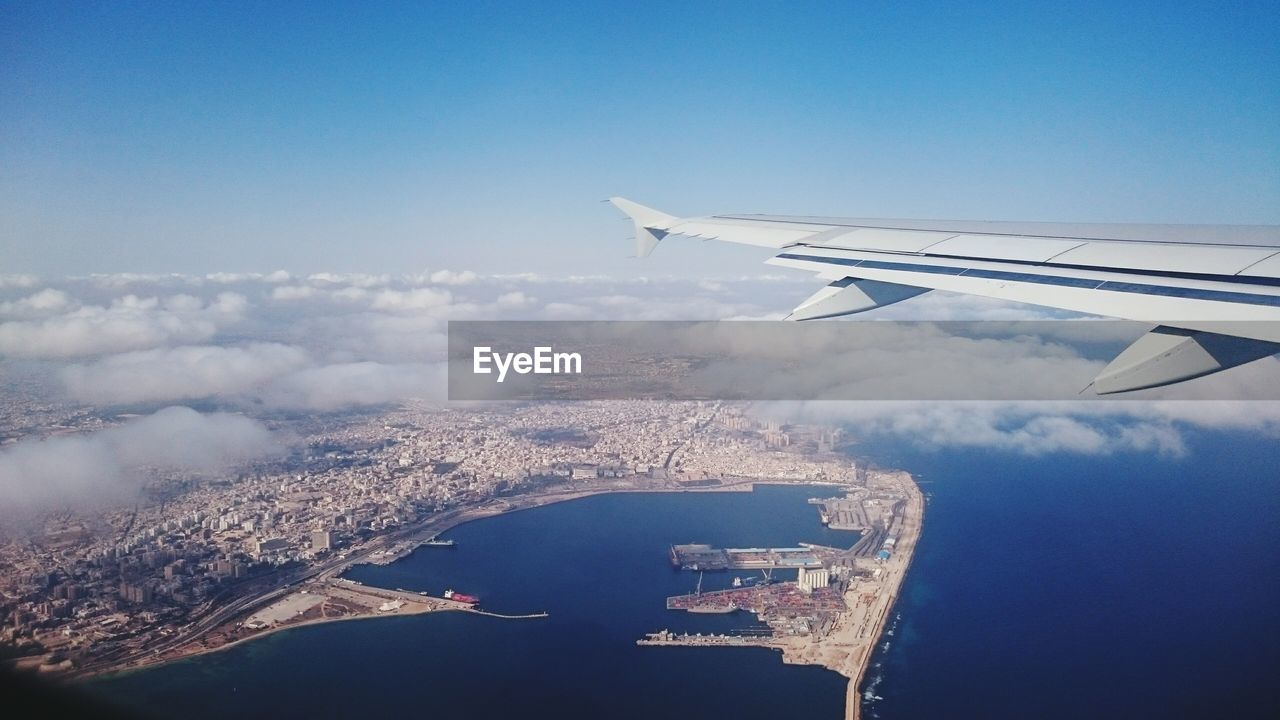 Cropped image of airplane flying over sea against sky