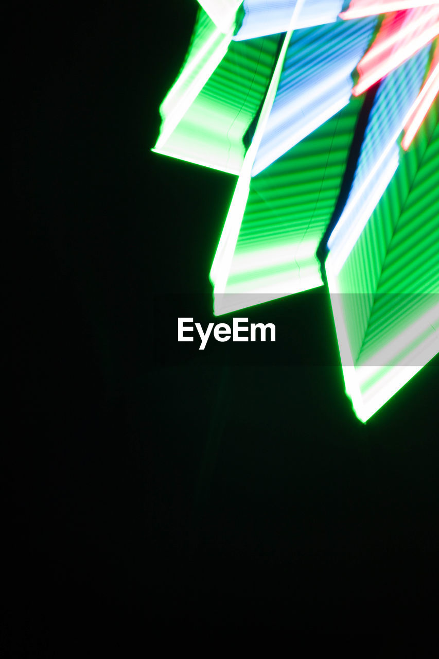 LOW ANGLE VIEW OF ILLUMINATED LIGHT OVER BLACK BACKGROUND