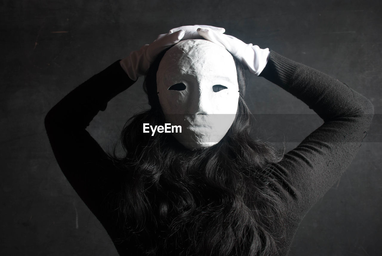 Rear view of woman wearing mask against wall