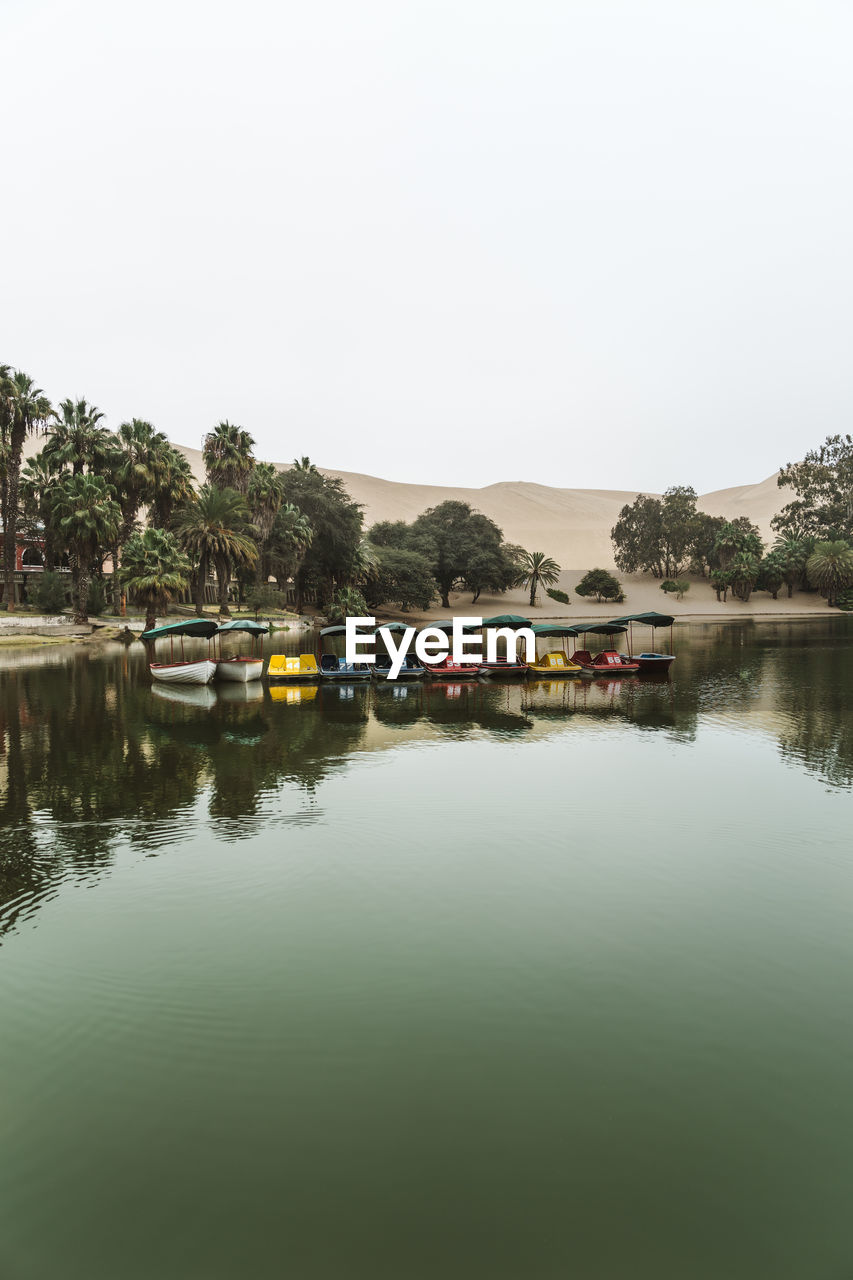 Boats moored on lake against clear sky