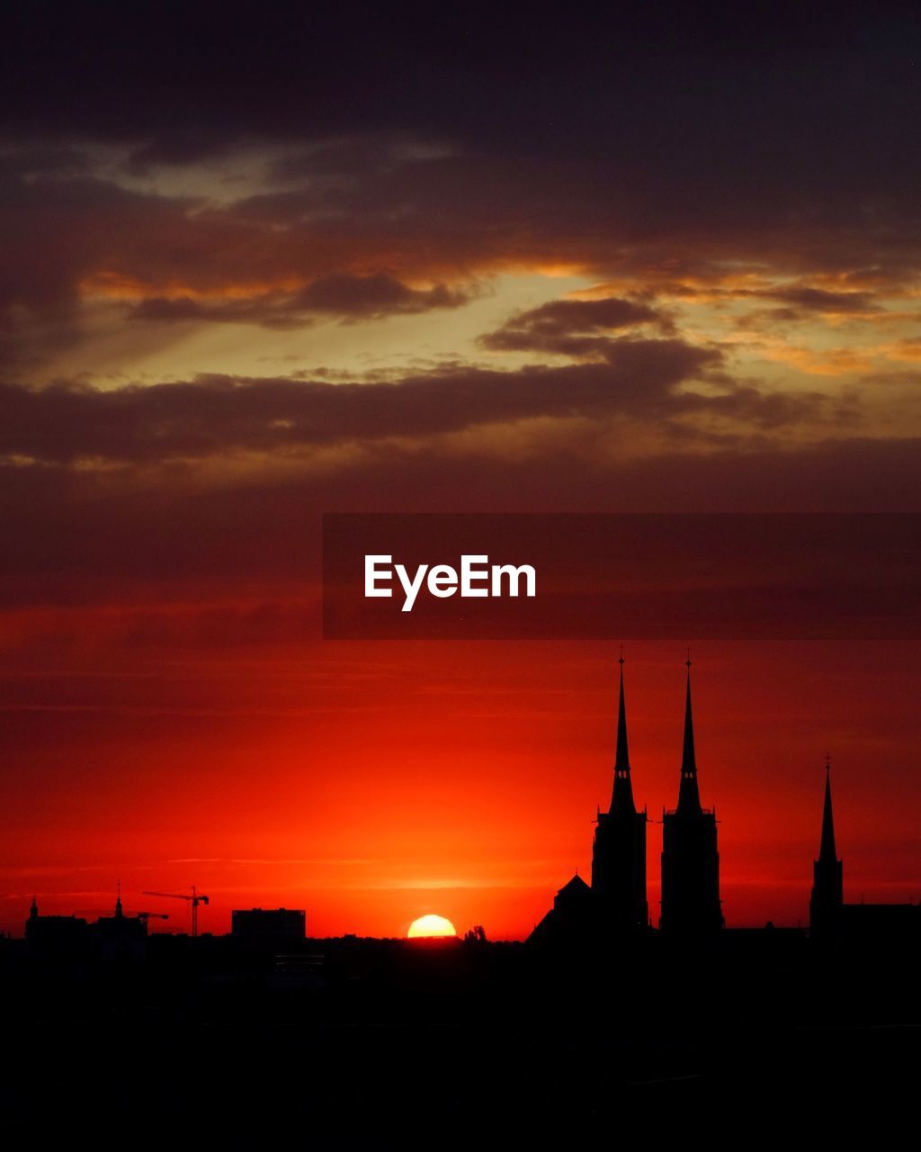 Silhouette of buildings against dramatic sky during sunset